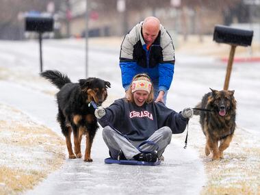 Kelsey Vining gets a push from Court Vining as she sleds down an icy sidewalk with dogs Mr...
