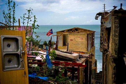 La bandera de Puerto Rico sobre escombros de una casa dañada tras el paso del huracán María...