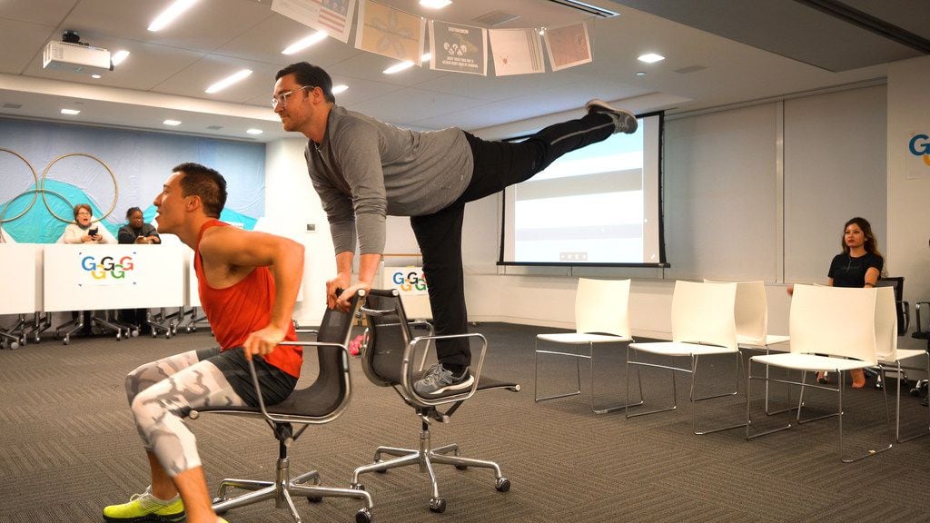 Gensler emplolyees Richard Lucio and Joshua Metzger glide on rolling office chairs at the...