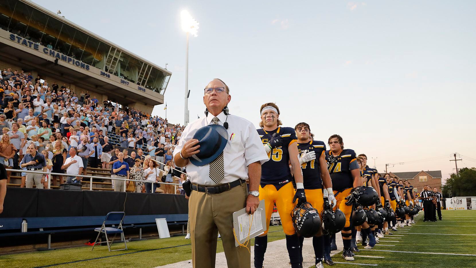 Highland Park High School head coach Randy Allen stands at attention with his team for the...