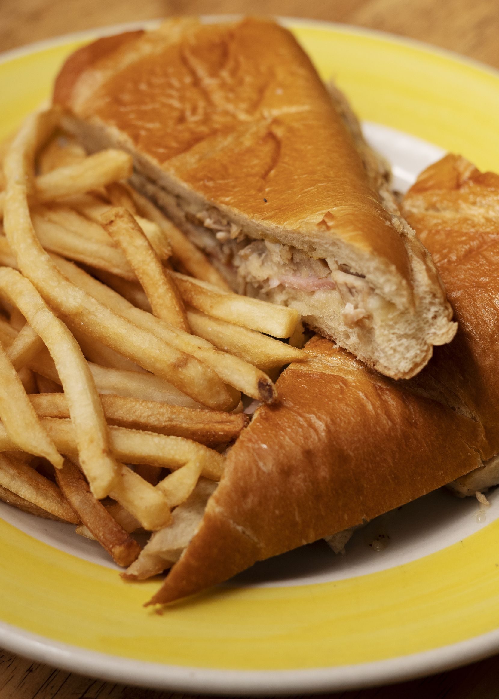 A Cubano sandwich with sliced pork, ham and Swiss cheese, served with fries, from Caribbean...