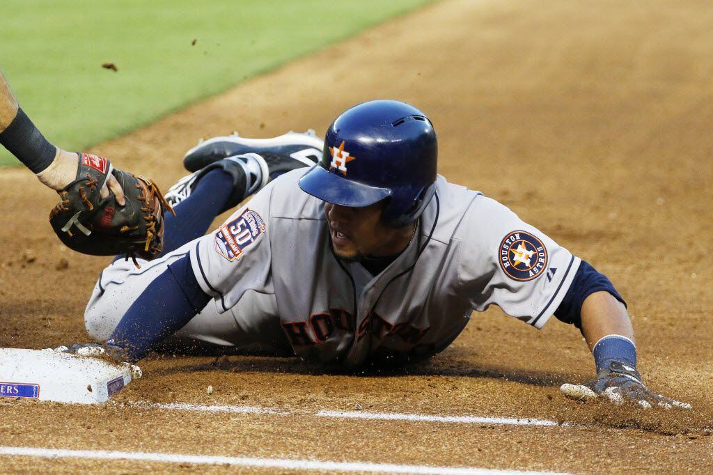 Houston Astros outfielder Carlos Gomez (30) dives back safely past the outstretched glove of...