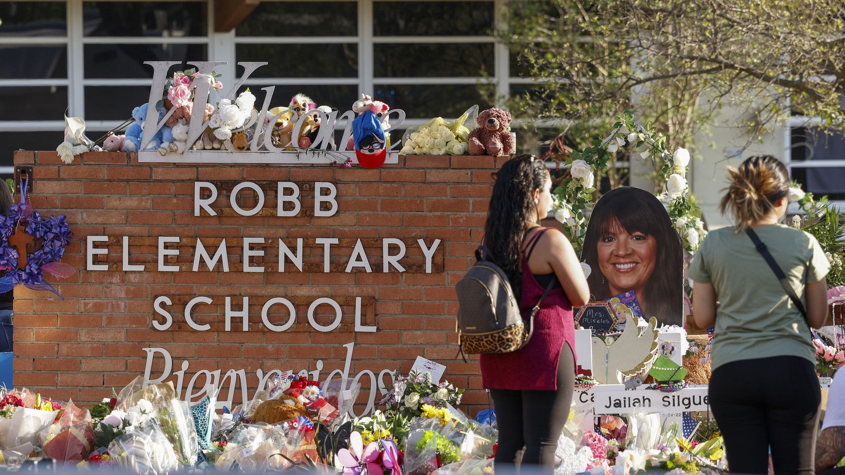People visit a memorial outside Robb Elementary School in Uvalde, where 19 children and two...