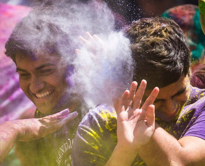 Celebrants are doused with colored powder during festivities celebrating the Hindu holiday...