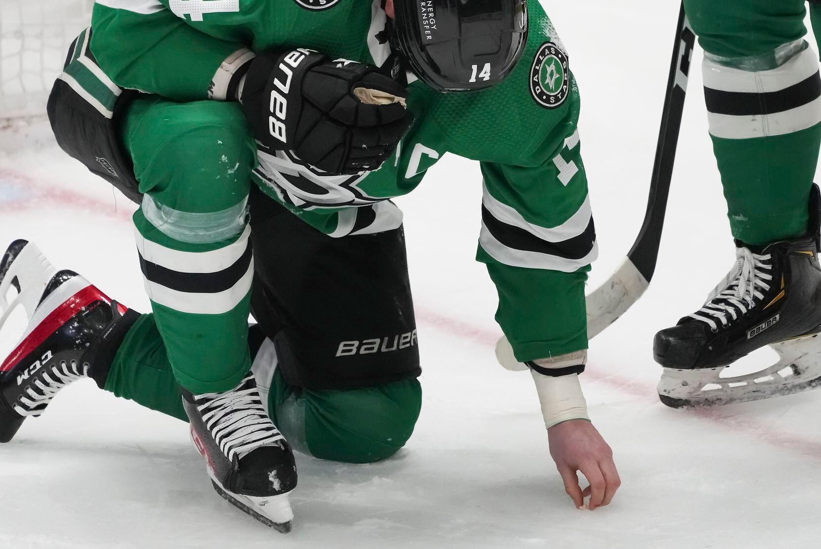 Dallas Stars left wing Jamie Benn (14) picks what appears to be a tooth up off the ice after...