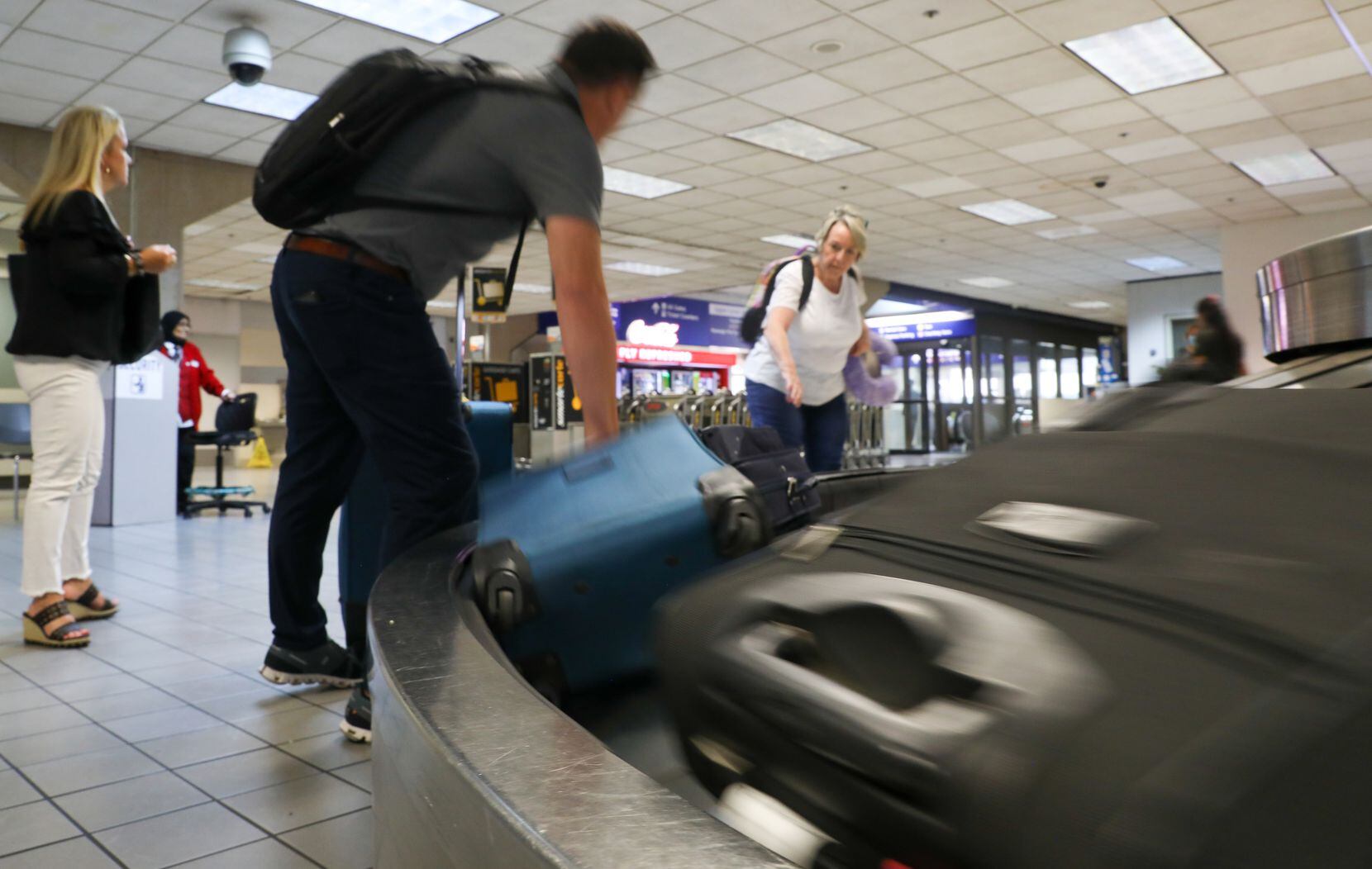 Judy Rose (right) collects her bags alongside other travelers at the Dallas Fort Worth...