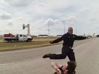 A frame from a police body camera shows Dallas firefighter Brad Cox kicking Kyle Robert Vess...