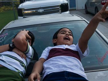 From left, brothers Jose Lara, 5, and Elias Lara, 7, gaze up at cloud shapes outside of...