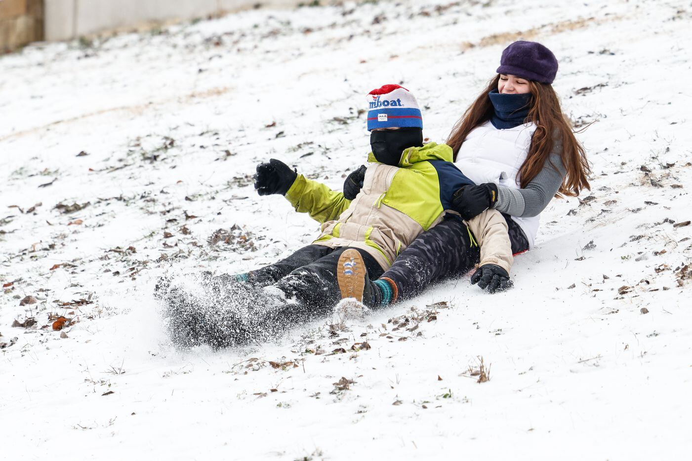 Mattheson Cano, 12, and Joselynn Cano, 15, slide down the hillside covered by sleet near at...