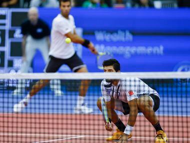 Marcelo Arevalo kneels allowing his teammate Jean-Julien Rojer to return the ball over him...