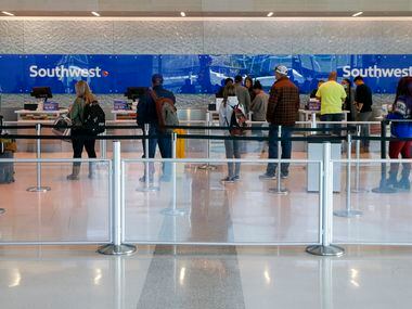 People wait in line for help at a Southwest Airlines ticket counter at Love Field Airport on...