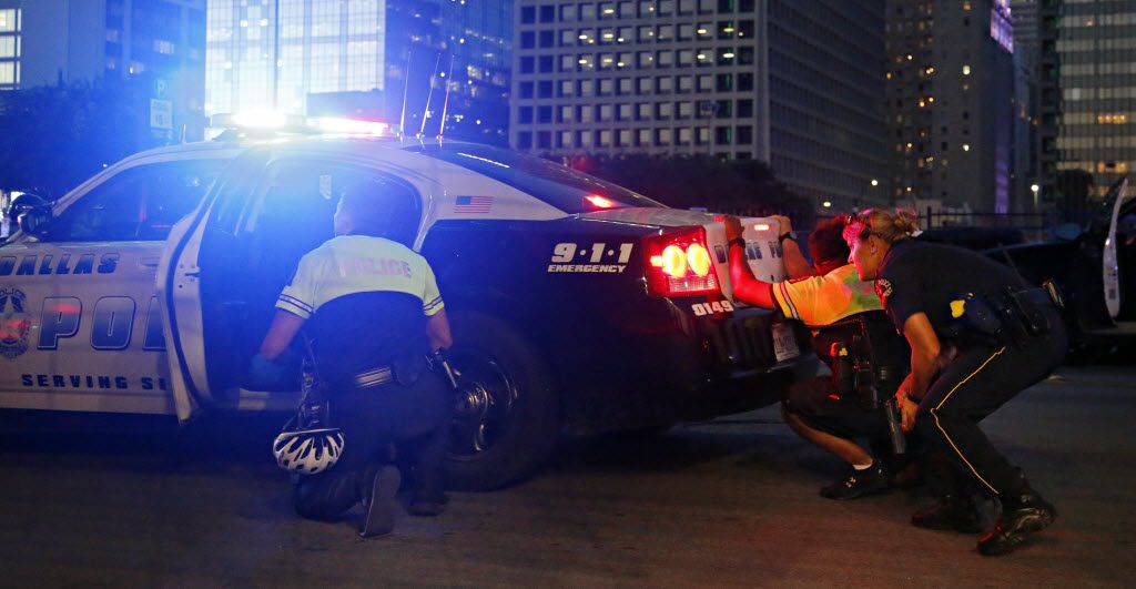 Dallas police officers hid behind a police cruiser as shots were fired on July 7.