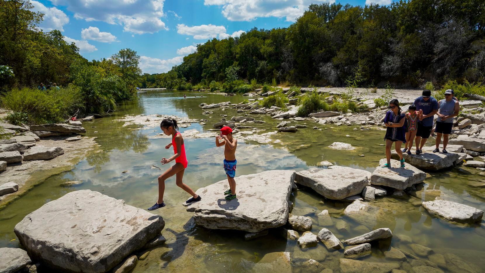 Park visitors cross the Paluxy River at Dinosaur Valley State Park in Glen Rose, one of...