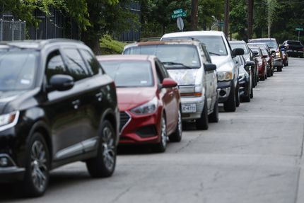 Cars line up along Holmes Street as they await entry to pick up groceries at the St....