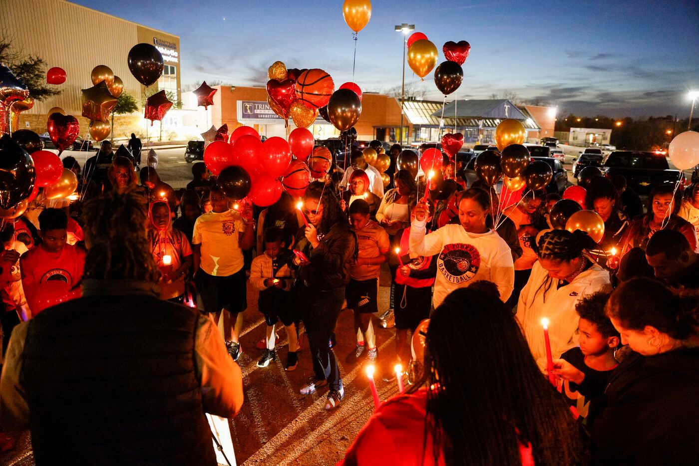People bow their heads during a prayer before releasing balloons in memory of 11-year-old...