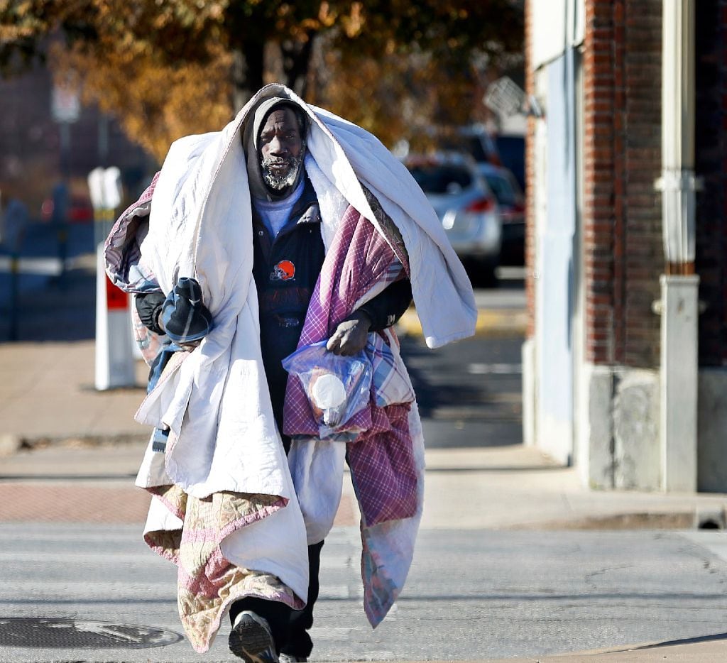 A homeless man, who didn't care to have his name mentioned, keeps warm under layers of...