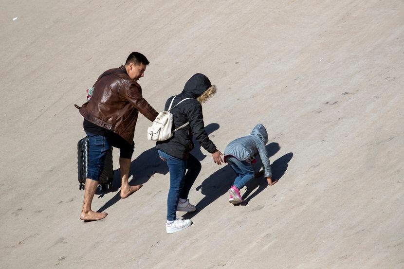 Una familia de migrantes sube por la orilla norte del río Bravo (Grande) después de cruzar...