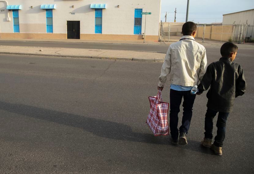 Carlos Joaquin Salinas, of Santa Rosa, Guatamala, crosses the street with his son Fernando...
