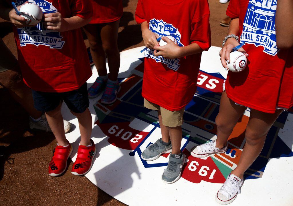 Young Rangers fans wait with their baseballs to be signed before a MLB game between Texas...