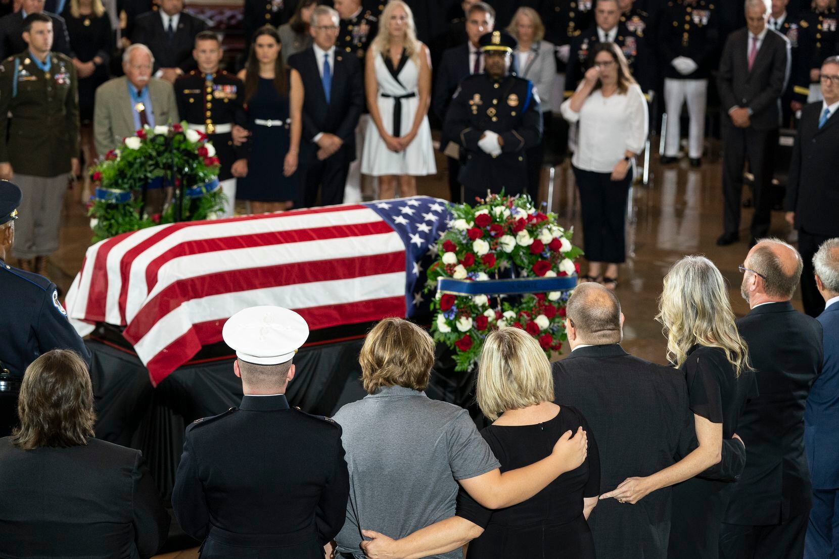 Medal of Honor recipients and family members surround the flag-draped casket bearing the...