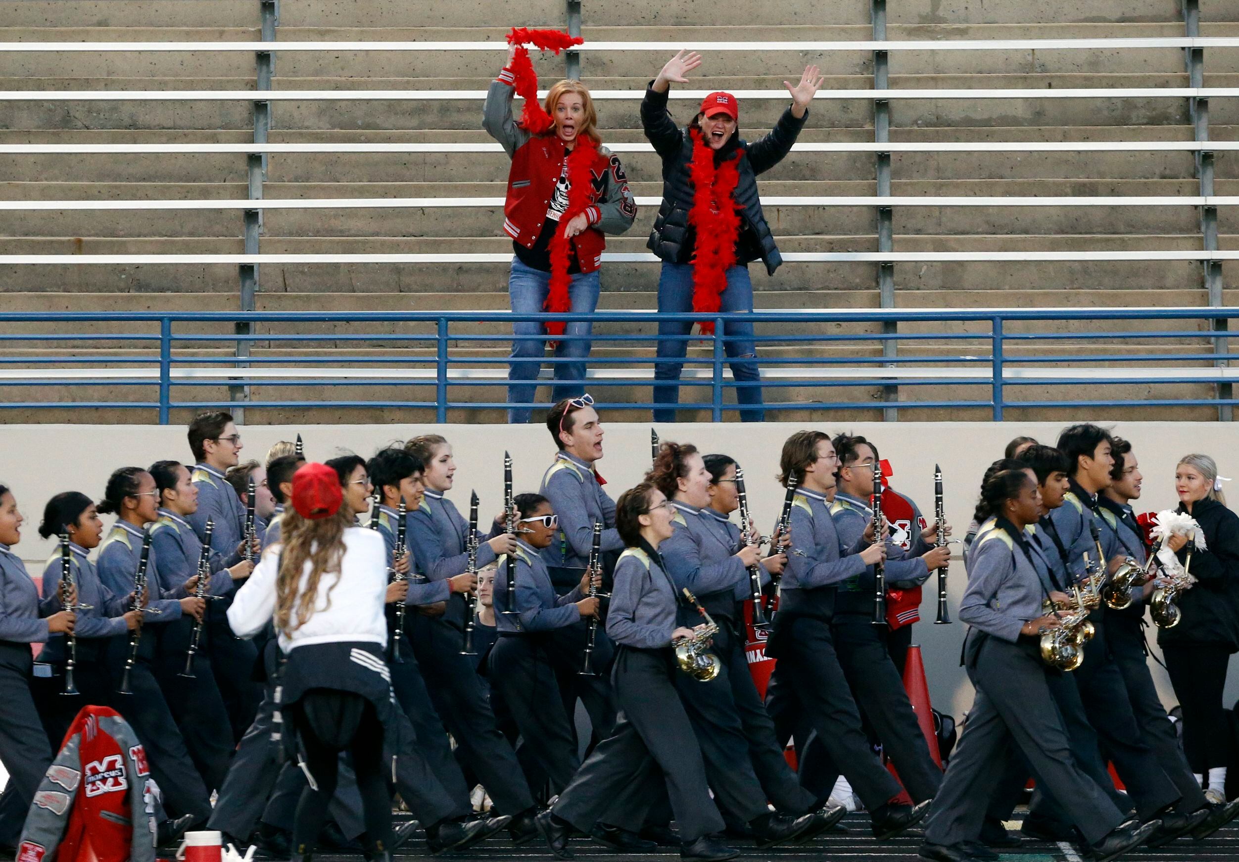 Two Flower Mound Marcus fans wave from the stands, as the Plano East high band marches in...