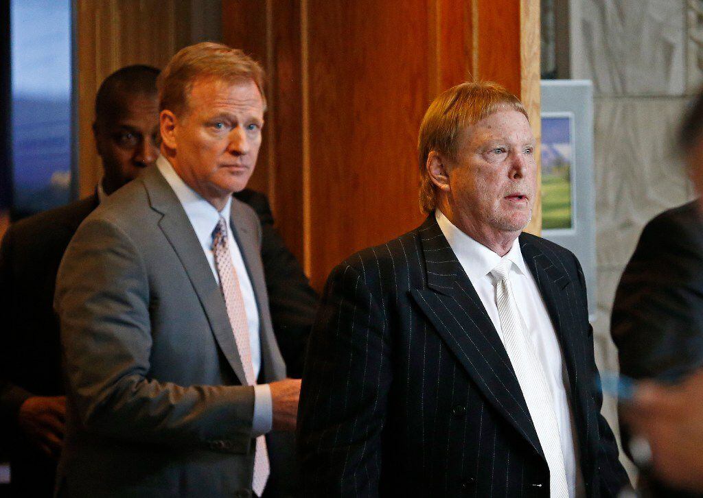 Oakland Raiders owner Mark Davis, right, emerges from the NFL football annual meetings with...