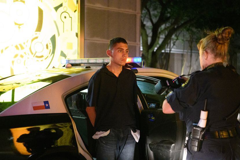 A Dallas Police Department crime scene analyst photographs Brian Hernandez outside the...