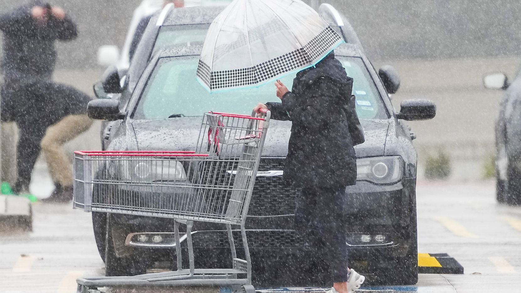 Shoppers at a Costco store in Plano navigate a cold rain in the parking lot on Monday, Jan....