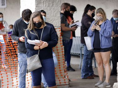 People wearing masks wait in line outside the Texas Department of Public Safety Drivers License Center in Garland.