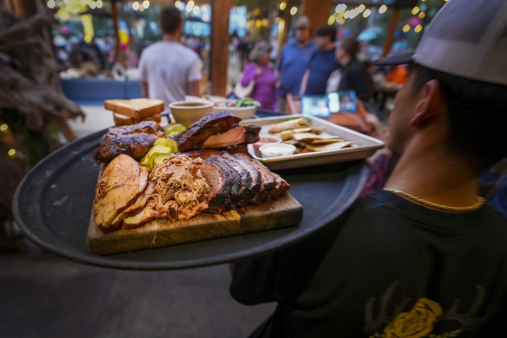 A board of signature smoked meats is delivered to a guest table at Smoky Rose restaurant. 