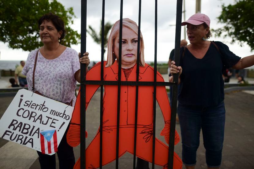 Manifestantes sostienen una imagen de la gobernadora de Puerto Rico, Wanda Vázquez, con ropa...