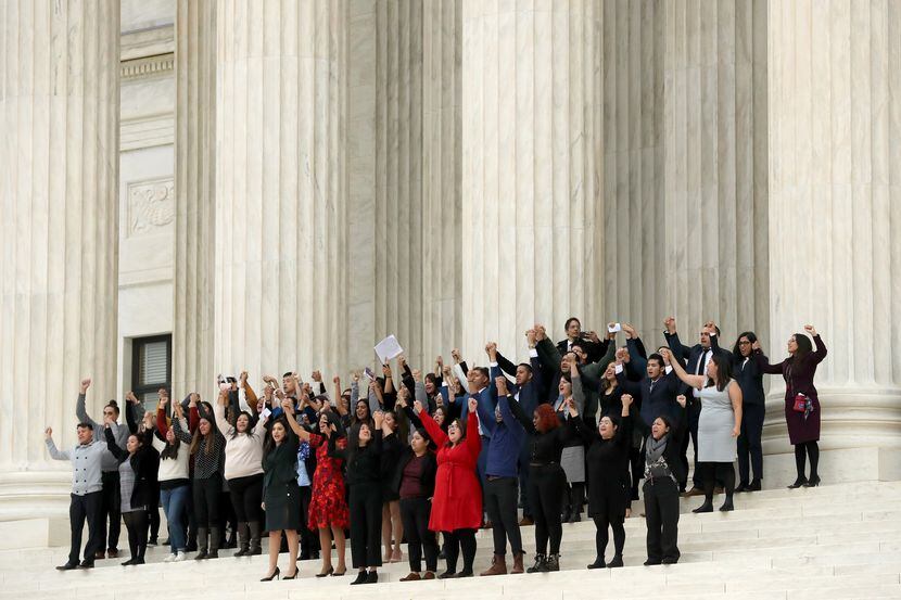 People raise their fists in the air and cheer Tuesday on the steps of the U.S. Supreme Court...
