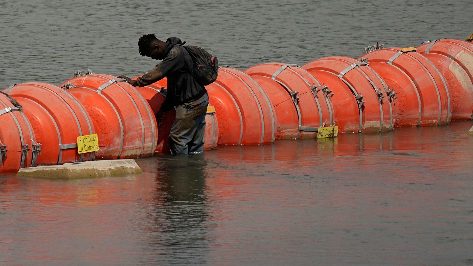 A migrant from Colombia stands at a floating buoy barrier as he looks to cross the Rio...