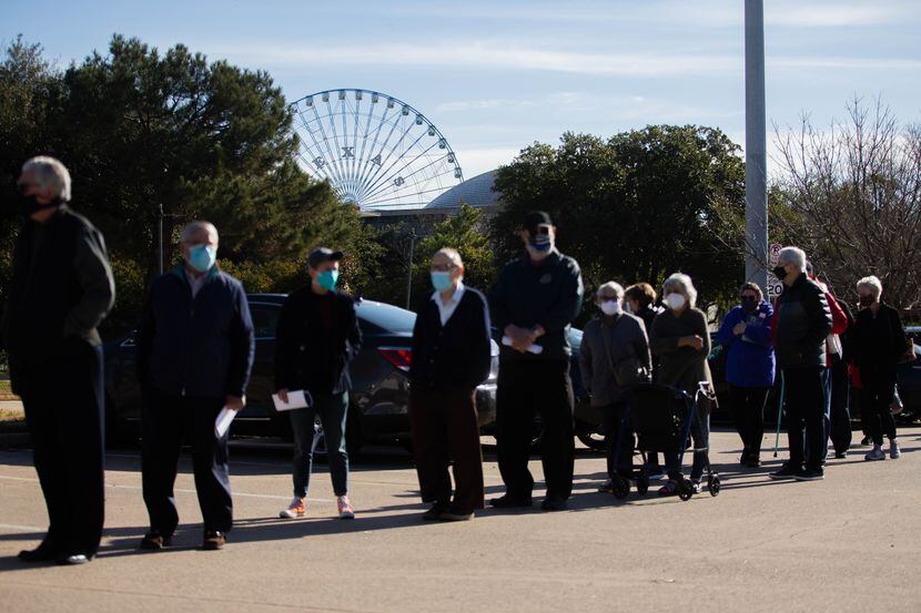 People wait in line for a golf cart in the parking lot of Fair Park before they receive the...