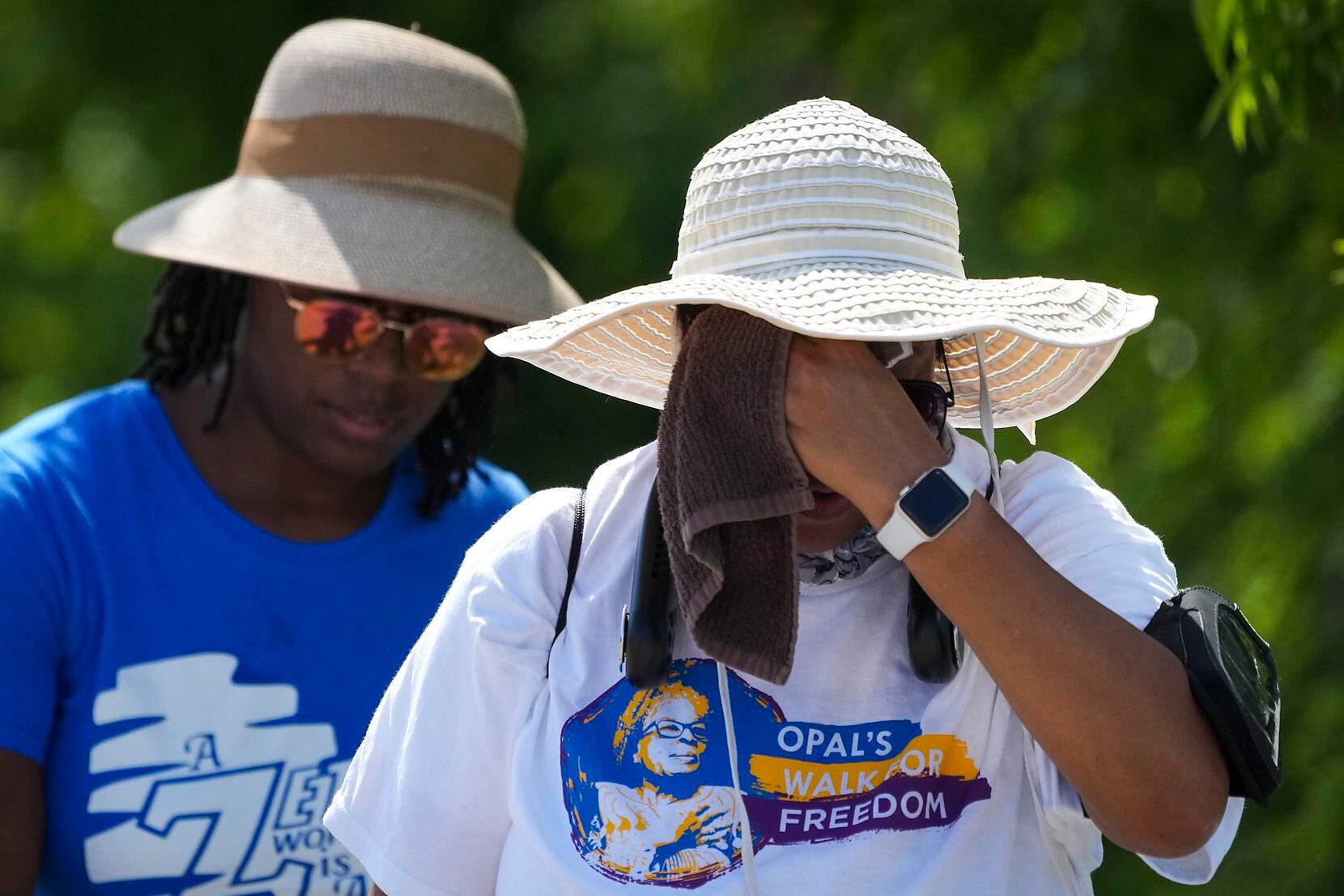 Walkers wipe away sweat during the 2022 Opal's Walk for Freedom on Saturday, June 18, 2022,...