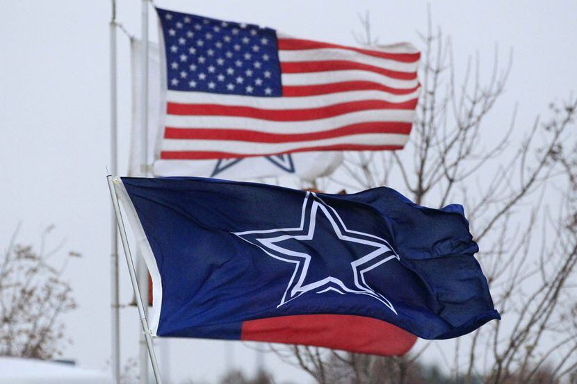 A brisk, cool wind blows a tailgater's flags horizontal on the AT&T stadium parking lot in...