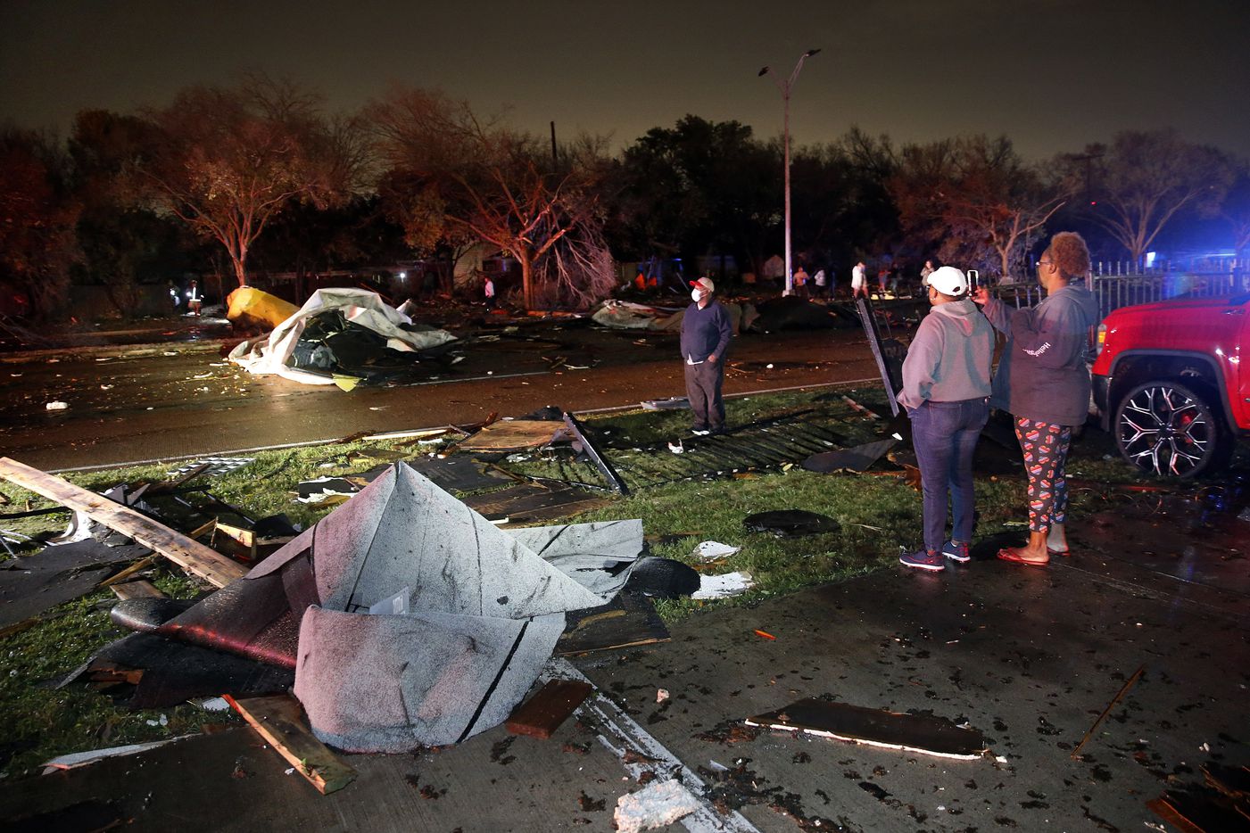 People inspect roofs of The Mirage Apartments that tore off and landed on Pioneer Parkway in Arlington following a tornado-warned storm, Tuesday night, November 24, 2020. (Tom Fox/The Dallas Morning News)