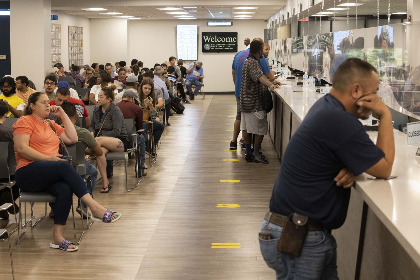 People wait for their number to be called at the Dallas County Tax Office located in the...