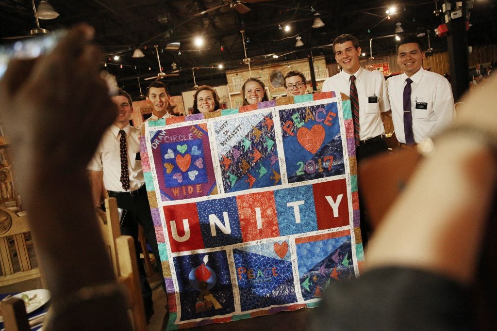 Members of the Church of Jesus Christ of Latter-day Saints take a pictures with a unity quilt designed by Faith Forward Dallas and the Oak Lawn United Methodist Church during the National Day of Prayer Luncheon.