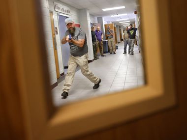 Henderson County Sheriff’s Deputy Kenneth Slatonapproaches an open classroom door as they...
