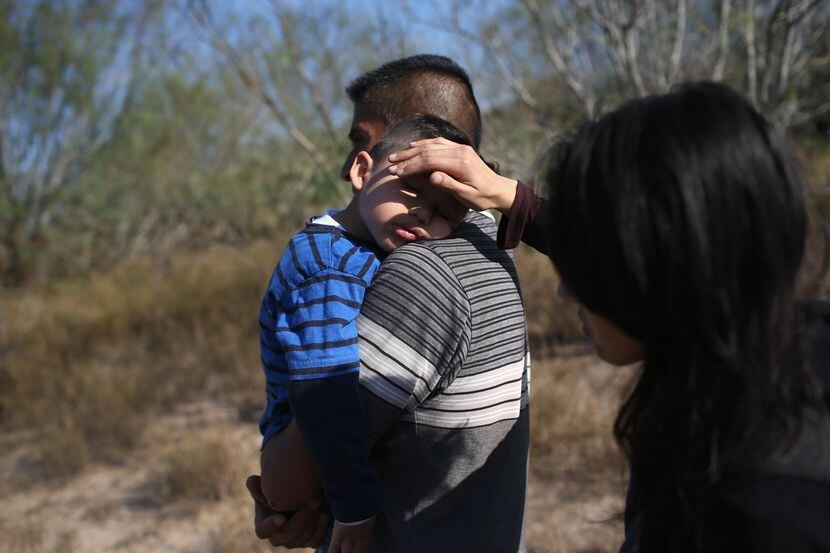 Una madre tapa el sol en la cara de su hijo luego de cruzar la frontera de México hacia...
