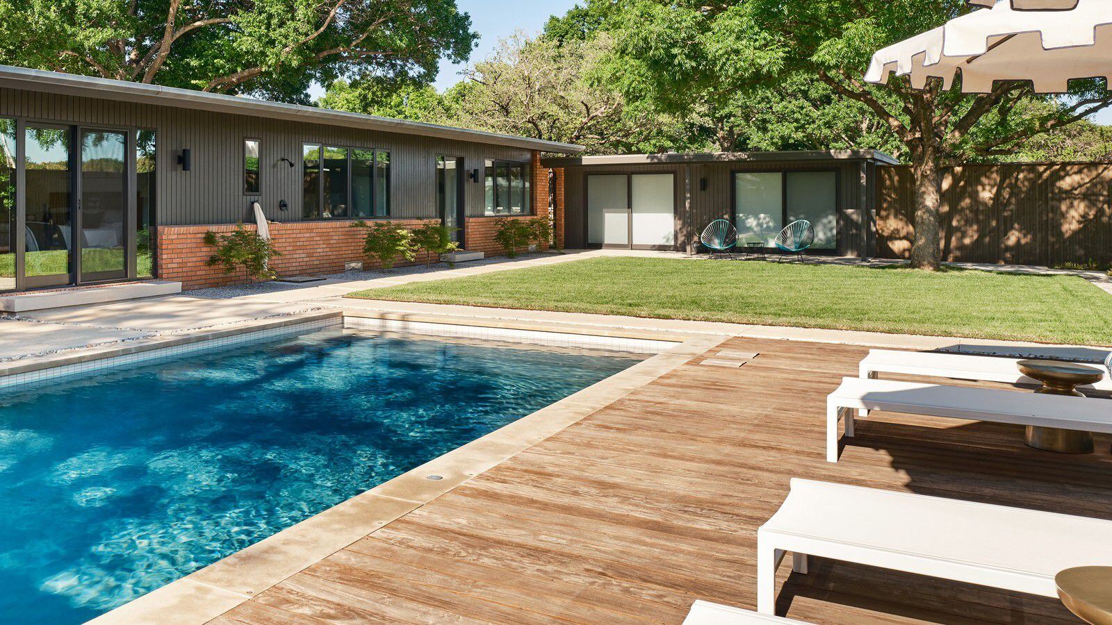 A midcentury modern home features a backyard with a pool.