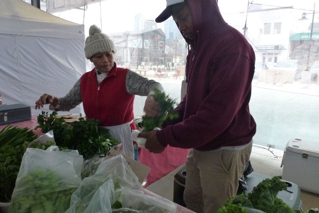 Sammy Williams helps his mom, Thongma Williams, bag up their parsley for a customer at the...
