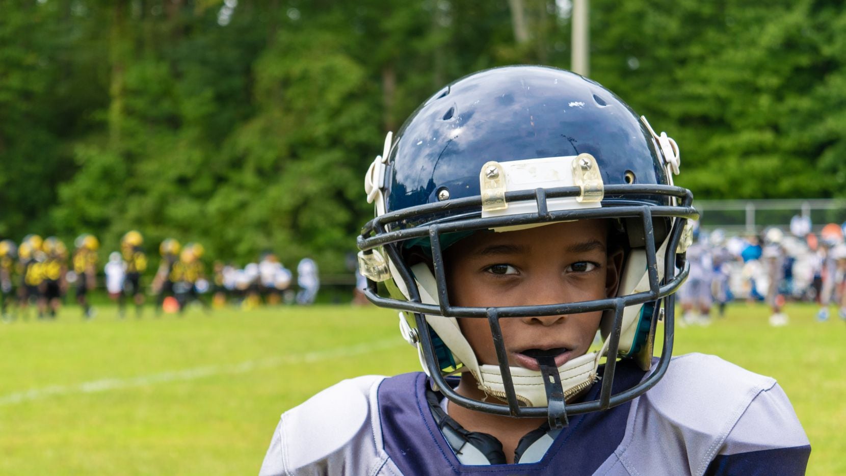 A young boy wearing a football helmet and uniform on a football field.