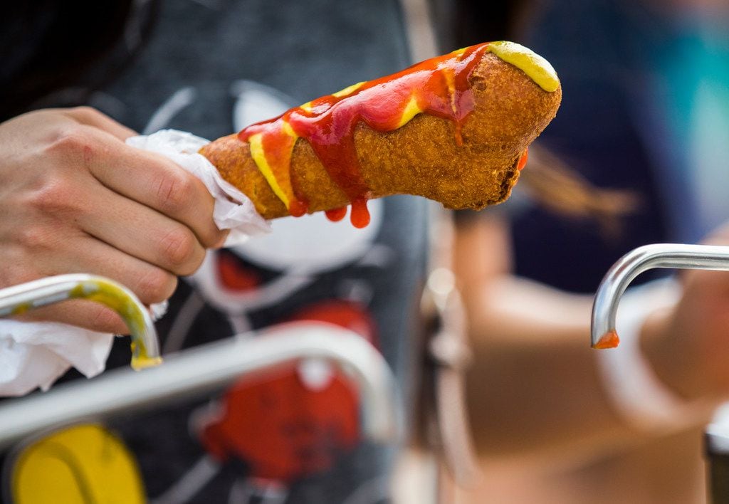 Monica Estrada tops her Fletcher's Corny Dog with mustard and ketchup at the State Fair of...