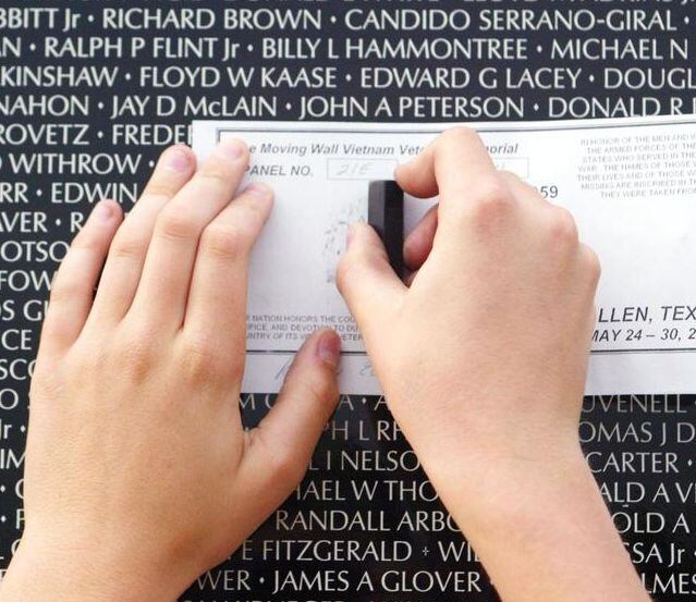 A visitor etches the name of a soldier killed in action during a visit to the Wall That...