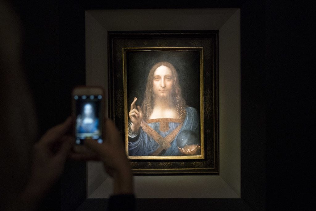 A visitor takes a photo of the painting Salvator Mundi by Leonardo da Vinci at Christie's...