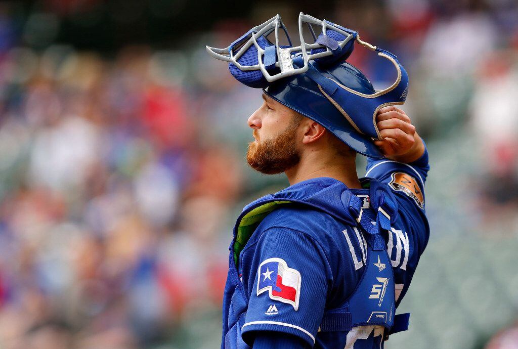 Texas Rangers catcher Jonathan Lucroy (25) pulls his mask back on during the first inning...