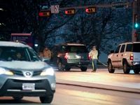 Two men work to pull a stick vehicle through the icy intersection of Greenville Avenue at...