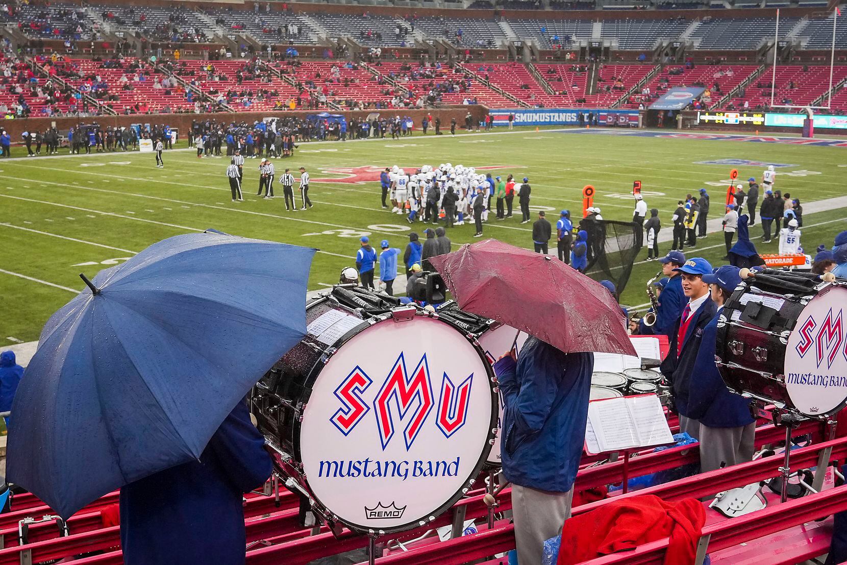 Members of the SMU band take cover from a light rain during the first half of an NCAA...